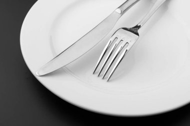 Koyu arkaplanda plakası olan çatal bıçak takımı.