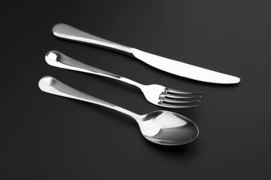 Siyah arka planda çatal bıçak ve kaşık.