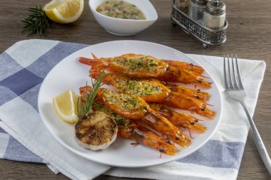 Ahşap bir masada ızgara sarımsaklı karides. 