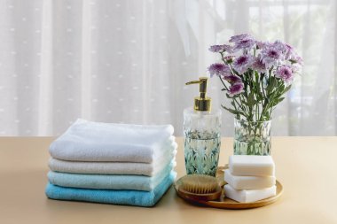 Açık mavi havlular, sabun, çiçekler ve ahşap arka planda banyo süslemeleri..