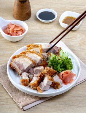 Tahta bir masada beyaz bir tabakta gevrek domuz göbeği.