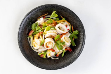 Baharatlı deniz ürünleri salatası, Tayland baharatlı yemek tarifi, siyah arka planda siyah tabakta baharatlı deniz ürünleri.