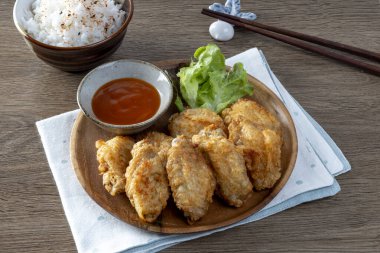 Tahta masada pilavla servis edilen kızarmış tavuk kanatları..