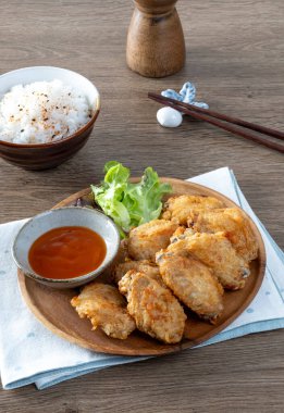 Tahta masada pilavla servis edilen kızarmış tavuk kanatları..