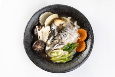 Soya çorbasında soya balığı kafası Japon usulü yemek malzemesiyle buğulanmış. Beyaz bir arkaplanda