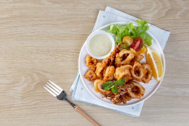Kızarmış Calamari: Baharatlı hamurla kaplanmış yumuşak kalamar halkaları, çıtır çıtır kızartmak için kızartılmış, soslu marinara veya aioli ile servis ediliyor..