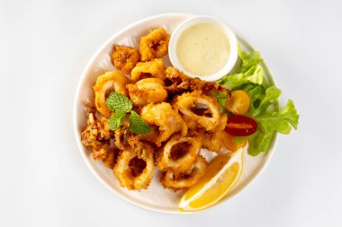 Kızarmış Calamari: Baharatlı hamurla kaplanmış yumuşak kalamar halkaları, çıtır çıtır kızartmak için kızartılmış, soslu marinara veya aioli ile servis ediliyor..