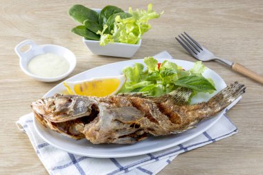 Kızarmış deniz levreği, beyaz bir tabakta, masada kızarana kadar kızardı.. 