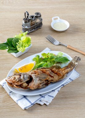 Kızarmış deniz levreği, beyaz bir tabakta, masada kızarana kadar kızardı.. 