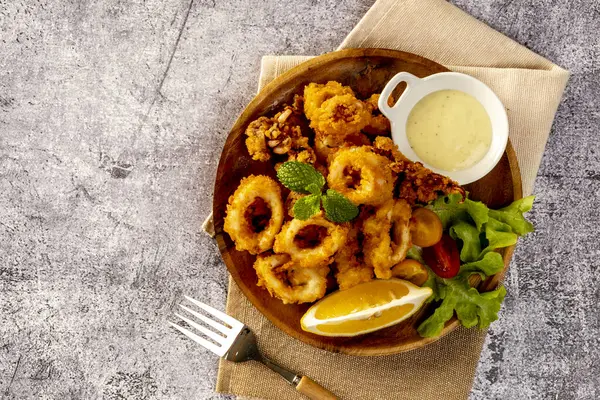 Baharatlı hamurla kaplanmış yumuşak kalamar halkaları, Tatar sosuyla servis edilir.