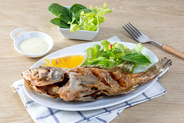 Kızarmış deniz levreği, beyaz bir tabakta, masada kızarana kadar kızardı.. 