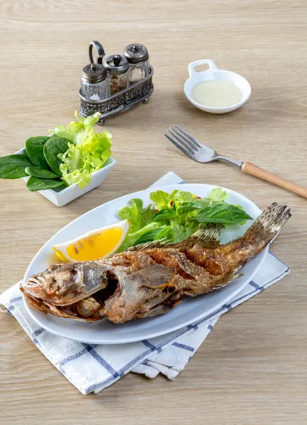 Kızarmış deniz levreği, beyaz bir tabakta, masada kızarana kadar kızardı.. 