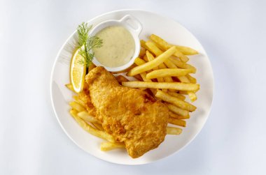 balık ve patates kızartması ve tartar sosuyla servis edilen dilimlenmiş limon beyaz arka planda izole edilmiş tabakta..