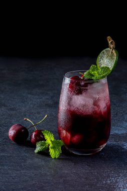 Taze kiraz kokteyl. Taze yaz kokteyl kiraz ve buz küpleri ile. Bardak vişne soda içecek karanlık taş zemin üzerine.