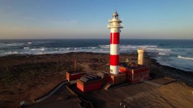 Gün batımında deniz feneri olan deniz manzarası. Hava aracı görüntüsü, Fuerteventura. Kanarya adası, El Cotilio köyü. El Toston Deniz Feneri