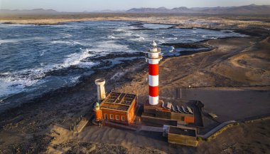 Gün batımında deniz feneri olan deniz manzarası. Hava aracı görüntüsü, Fuerteventura. Kanarya adası, El Cotilio köyü. El Toston Deniz Feneri