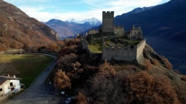  Medieval impressive castle Cly surrouded by Alps mountains in Valle d'aosta, aerial drone view