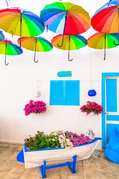 Beautiful street bar (restaurant) decoration with colorful umbrellas, old wooden boat and flowers. Bodrum,Turkey