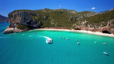 Sardegna Adası 'nın (İtalya) en iyi ve en güzel plajları Orosei Körfezi' ndeki Cala Luna. Beyaz kumlu sahil, mağaralar ve turkuaz deniz manzaralı hava aracı. yüksek açı 4khd video