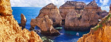Algarve Sahili, Portekiz 'in inanılmaz kayalık manzaralı partileri. Nefes kesen ünlü Praia da Marinha plajı, üzerinde sarı yay olan kayalar. panoramik yaşam