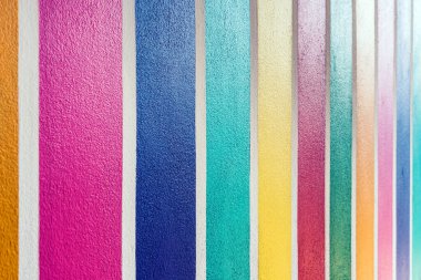 Beton duvarda çok renkli çizgili desen var. Duvarın çimento yüzeyine renkli boyanmış. Gökkuşağı renginde grafiti. Duvarlarla dolu bir renk. Renkli çit, çok renkli beton çit..