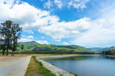 Etrafı dağlarla çevrili güzel ve huzurlu bir göl ve güzel güneş ışığı ve Tayland 'da bulutlu bir gökyüzü. Huzurlu ve güzel doğal bir göl manzarası..