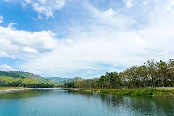 stock image Beautiful and peaceful view of large reservoir with surrounding mountain and trees in beautiful sunshine and cloudy sky in Thailand. Tranquil and beautiful natural scenery landscape of reservoir lake.