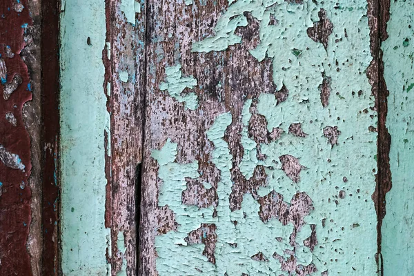 木门底座上的脱层油漆色彩艳丽 木制纹理背景与老油漆皮 风干的木头用好几层破烂不堪的旧油漆 矮小的木墙 — 图库照片