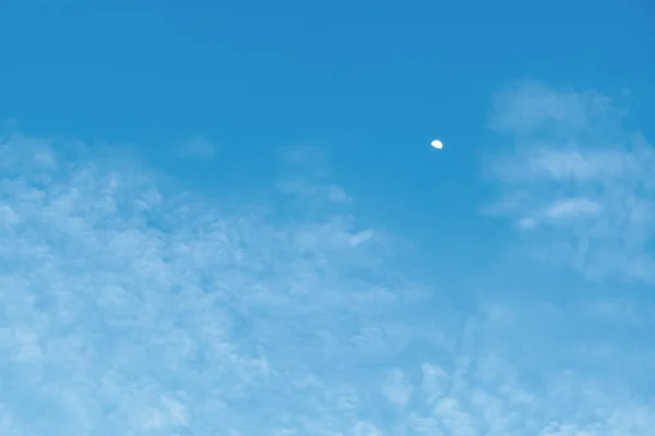 Half moon in sky in daytime with wispy clouds environment atmosphere. Natural moon and sky background texture, The free form beauty of clouds and sky is perfect for background, backdrop and wallpaper.
