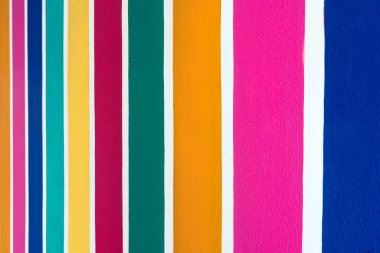 Beton duvarda çok renkli çizgili desen var. Duvarın çimento yüzeyine renkli boyanmış. Gökkuşağı renginde grafiti. Duvarlarla dolu bir renk. Renkli çit, çok renkli beton çit..