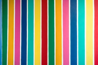 Beton duvarda çok renkli çizgili desen var. Duvarın çimento yüzeyine renkli boyanmış. Gökkuşağı renginde grafiti. Duvarlarla dolu bir renk. Renkli çit, çok renkli beton çit..