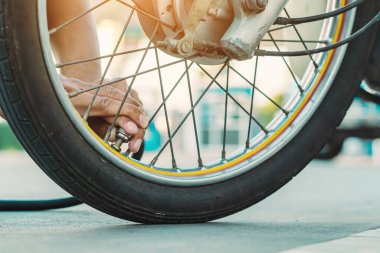 Adamın elleri enflasyon basıncını ölçer ve motorun lastiğini hava kompresörüyle şişirir. Adam hava basıncını kontrol ediyor ve otomatik hava doldurucudan motosiklet tekerindeki lastik basıncını dolduruyor..