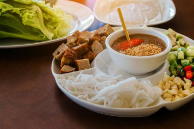 Close up to dipping sauce for Vietnamese Meatball Wraps (Nam-Neung), Pork Sausage wraps with fresh vegetables in rice paper, generous platter eat with sweet sauce. Vietnamese Pork Sausage and salad.