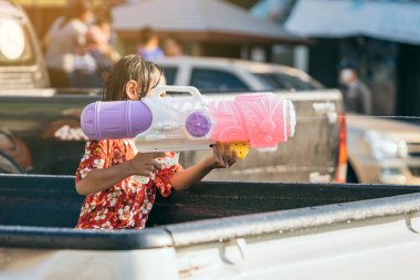 Songkran festivalinde halka su tabancasıyla ateş eden küçük bir kızın elleri. Taylandlılar Kanchanaburi, Tayland 'da birbirlerine su sıçratarak Songkran' ı kutluyorlar..