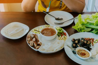 Close up to dipping sauce for Vietnamese Meatball Wraps (Nam-Neung), Pork Sausage wraps with fresh vegetables in rice paper, generous platter eat with sweet sauce. Vietnamese Pork Sausage and salad.