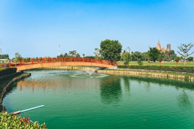 Japon tarzı kırmızı ahşap köprünün zümrüt göl üzerindeki manzarası. Çeltik tarlalarının doğasına aykırı çeşmeleri var. Eşsiz kırmızı ahşap köprüsü olan Japon tarzı bir bahçe. Güzel manzara.