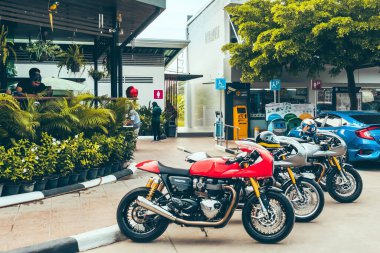 KANCHANABURI - THAILAND, NOVEMBER 7, 2020: PTT benzin istasyonunda eski moda Triumph Thruxton önleme aracı eski model motosikletleri Amazon kahve dükkanının (Kafe Amazon) önünde durdurdu.