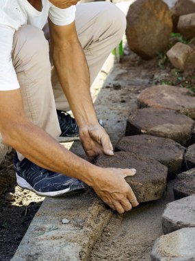 İşçilerin elleri sığdırır ve taş kaldırımları sıraya dizer. Sekizgen Bricks Yolu 'nun inşaatı. Kurulum veya yenileme onarımı. Döşeme levhaları seriyor. Ellere seçici odaklanma.