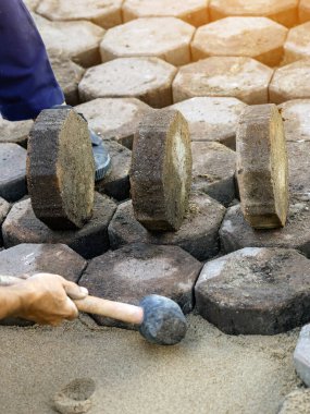 Sekizgen Bricks Yolu 'nun inşaatı. Kurulum veya yenileme onarımı. Tuğlacı kaldırıma oturur ve kaldırım levhalarını serer. Döşeme levhaları seriyor. Sekizgen tuğlalarına odaklan.