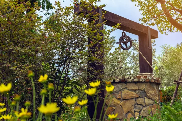 Beautiful artesian well made by stones and wheel pulley with metal
