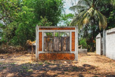 Kırık kapıları ve pencereleri olan terk edilmiş eski bir tuğla evin dışında. Tamamlanmamış ve terk edilmiş bir ev. Banliyöde inşaat halindeki tek aile evinin beton dış cephesi.