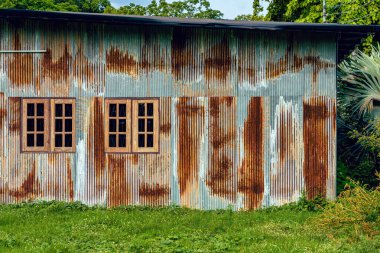 Eski çinko duvarlı ön cephe evi. Güzel bir galvanizli çarşaf evin dış yüzünü güzelleştirir. Ev duvarı yapmak için malzeme içeren paslı galvanize demir çarşaf. Eski pas galvanizli çarşafın aşınması.