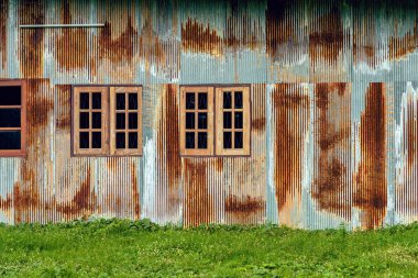 Eski çinko duvarlı ön cephe evi. Güzel bir galvanizli çarşaf evin dış yüzünü güzelleştirir. Ev duvarı yapmak için malzeme içeren paslı galvanize demir çarşaf. Eski pas galvanizli çarşafın aşınması.