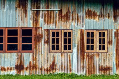 Eski çinko duvarlı ön cephe evi. Güzel bir galvanizli çarşaf evin dış yüzünü güzelleştirir. Ev duvarı yapmak için malzeme içeren paslı galvanize demir çarşaf. Eski pas galvanizli çarşafın aşınması.