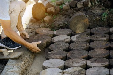 İşçilerin elleri sığdırır ve taş kaldırımları sıraya dizer. Sekizgen Bricks Yolu 'nun inşaatı. Kurulum veya yenileme onarımı. Döşeme levhaları seriyor. Ellere seçici odaklanma.