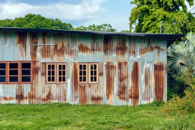 Eski çinko duvarlı ön cephe evi. Güzel bir galvanizli çarşaf evin dış yüzünü güzelleştirir. Ev duvarı yapmak için malzeme içeren paslı galvanize demir çarşaf. Eski pas galvanizli çarşafın aşınması.