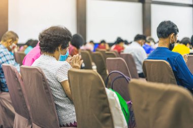 Son sınıf öğrencisi kadın yüz maskesi takıyor ve konferans salonundaki yıllık toplantıyı dinliyor. Konferans odasında Asyalı yaşlı katılımcılar. İş konferansının neşeli dinleyicileri.