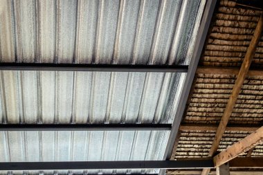 Tavan yalıtımla kaplı ve sazdan çatıyla birleştirilmiş. Alüminyum folyo ısı radyasyonunu yansıtmak için çatı altına yerleştirildi. Tavan arası yalıtımı. Karışık malzeme yapısının çatı yüzeyi detayı.