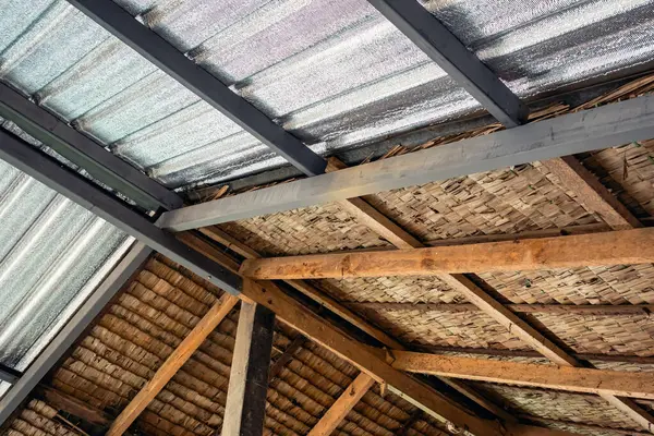 Ceiling covered with insulation combined with thatched roof. Aluminum foil installed under roof for reflect heat radiation. Attic insulation. Roof surface detail of mixed materials pattern structure.