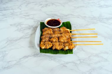 Tayland baharatlı soslu ızgara timsah bifteği mi yoksa mermer arka planda muz yaprağının üzerinde Jaew sosu mu? Barbekü soslu timsah. Masadaki beyaz tabakta kızarmış timsah eti..